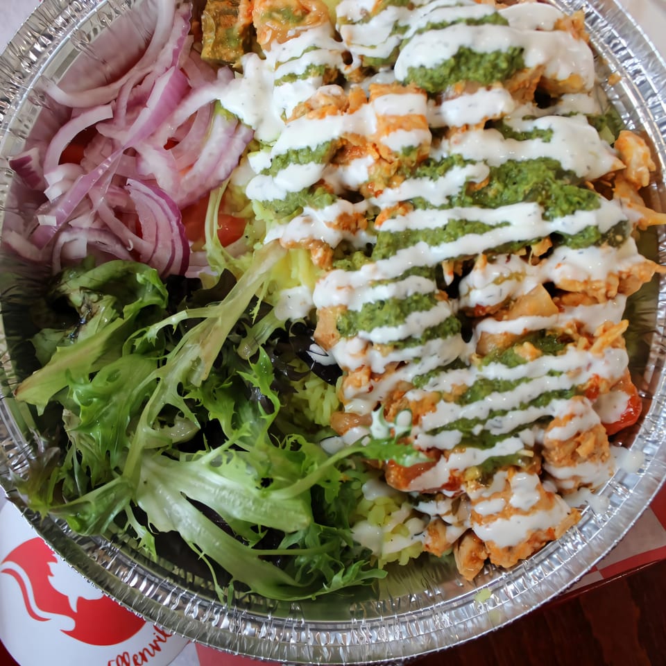 Ellenville Spice Fusion's fried chicken bowl with lettuce, red onions, and two sauces.