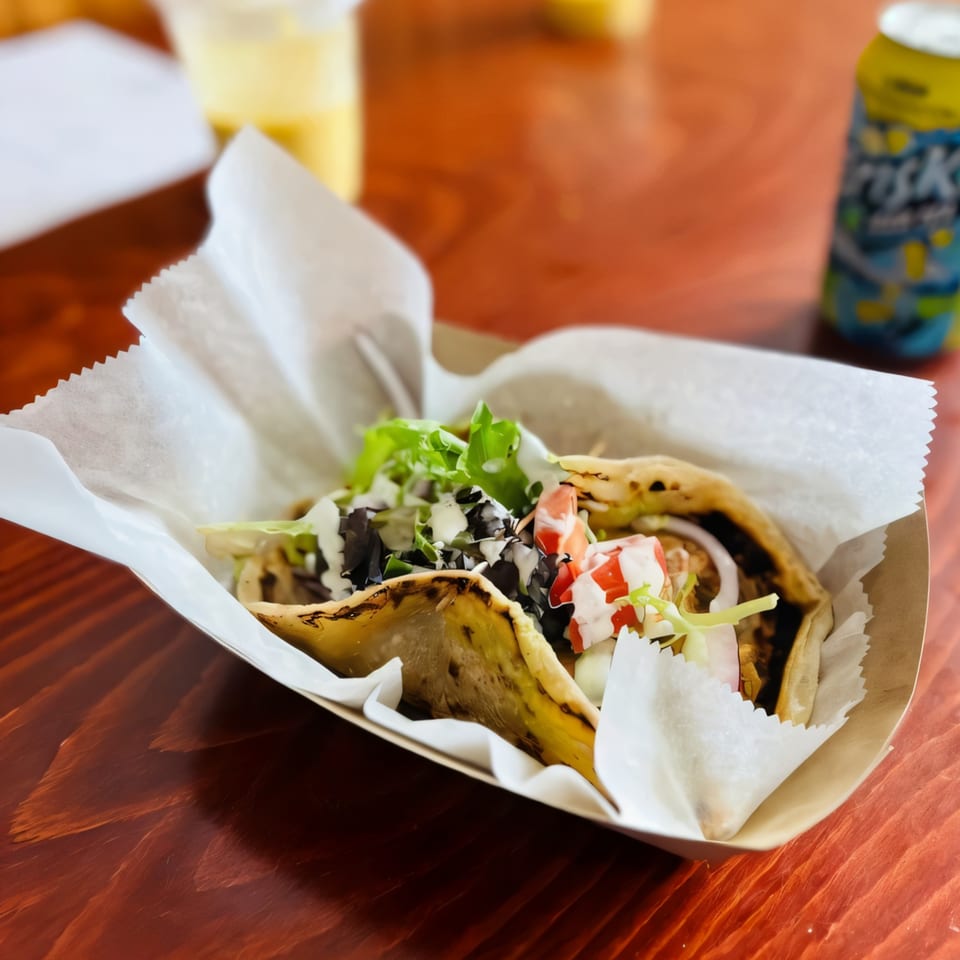 Two Ellenville Spice Fusion tacos with lettuce, tomato, and sauce in a paper tray.